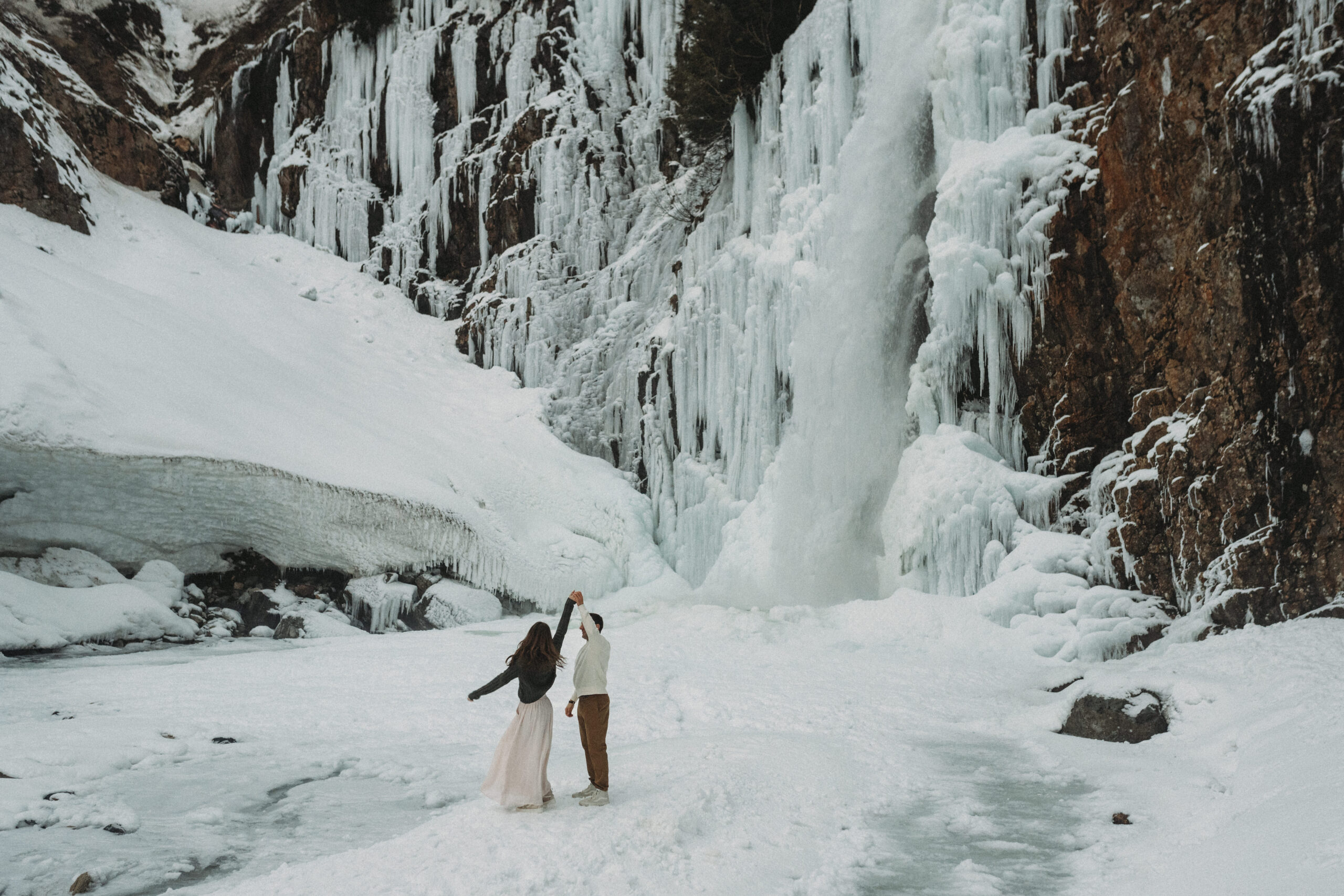 couple dancing beneath winter waterfall at franklin falls in washington state